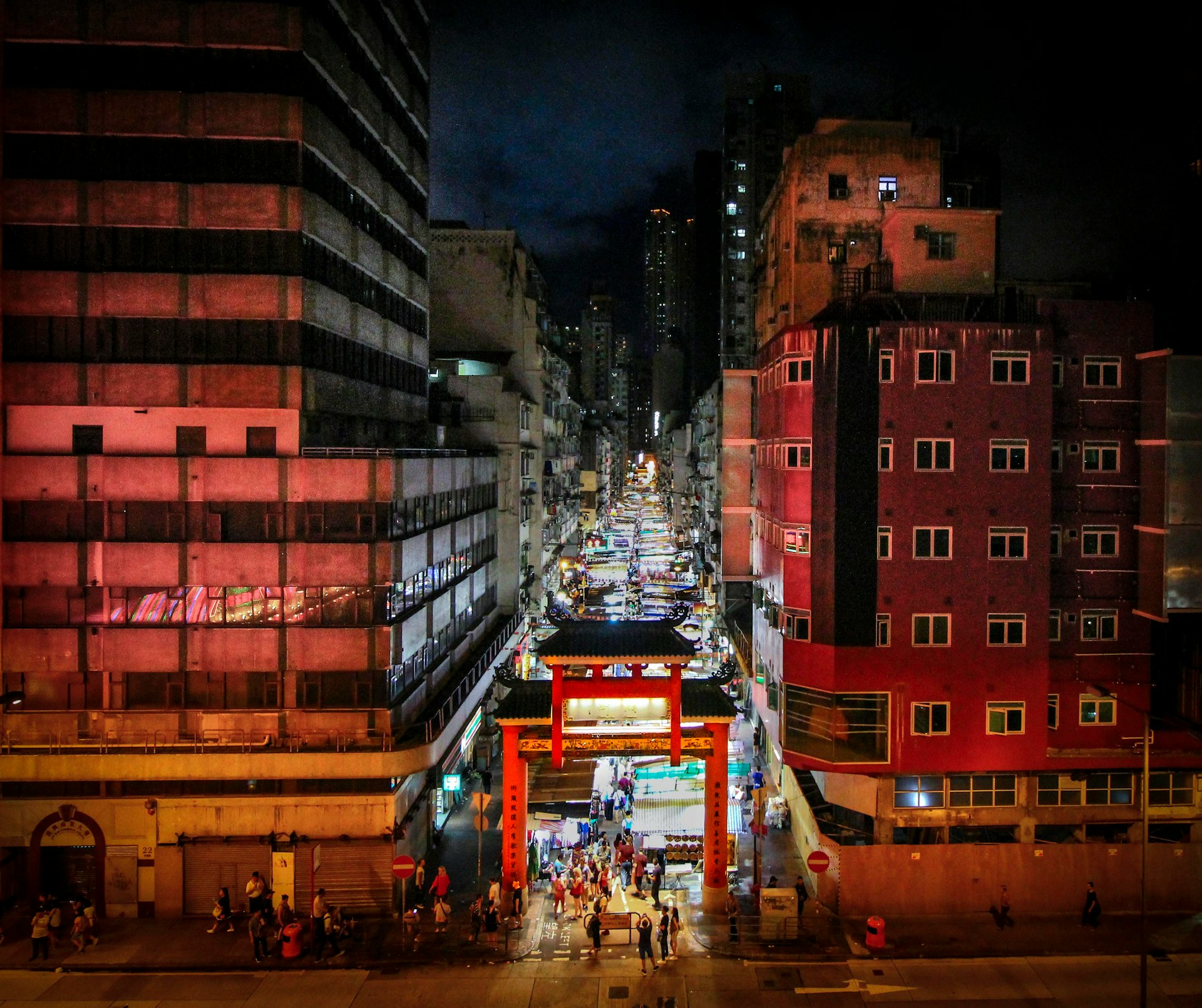 people walking between buildings at night